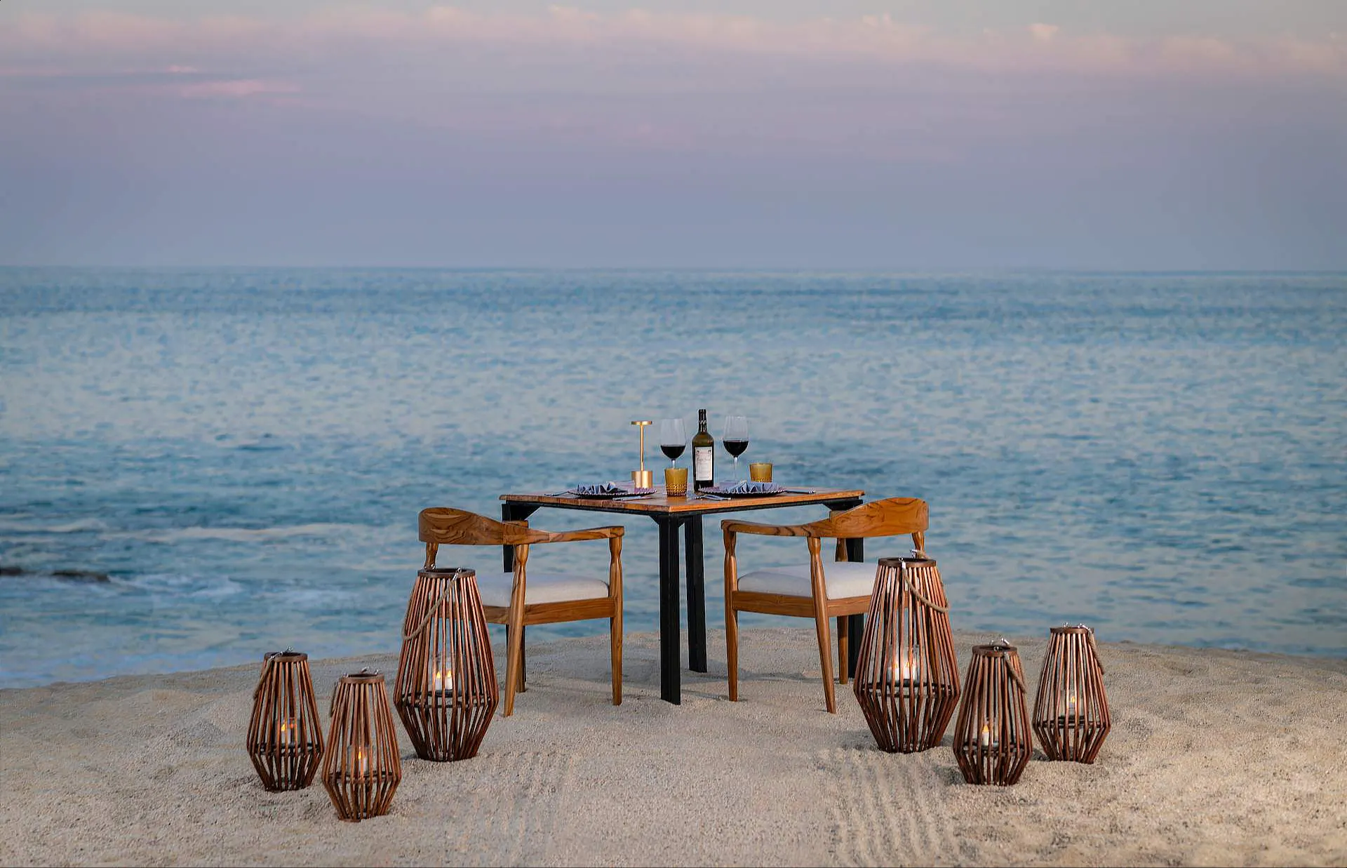 Cena romántica a la luz de las velas en la arena junto al océano.