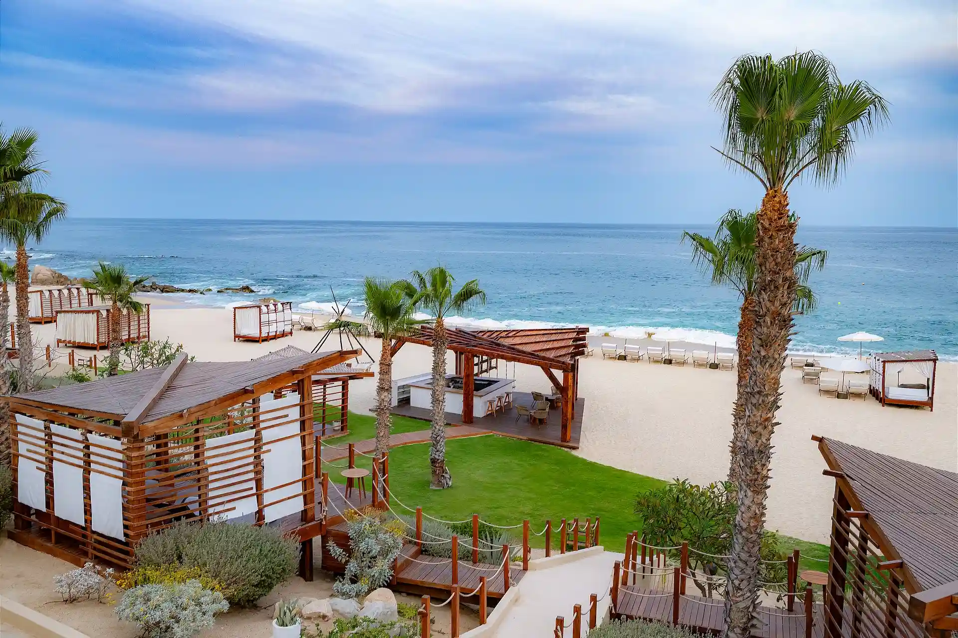 Cabañas de playa frente al mar y palmeras con vista al tranquilo mar azul.