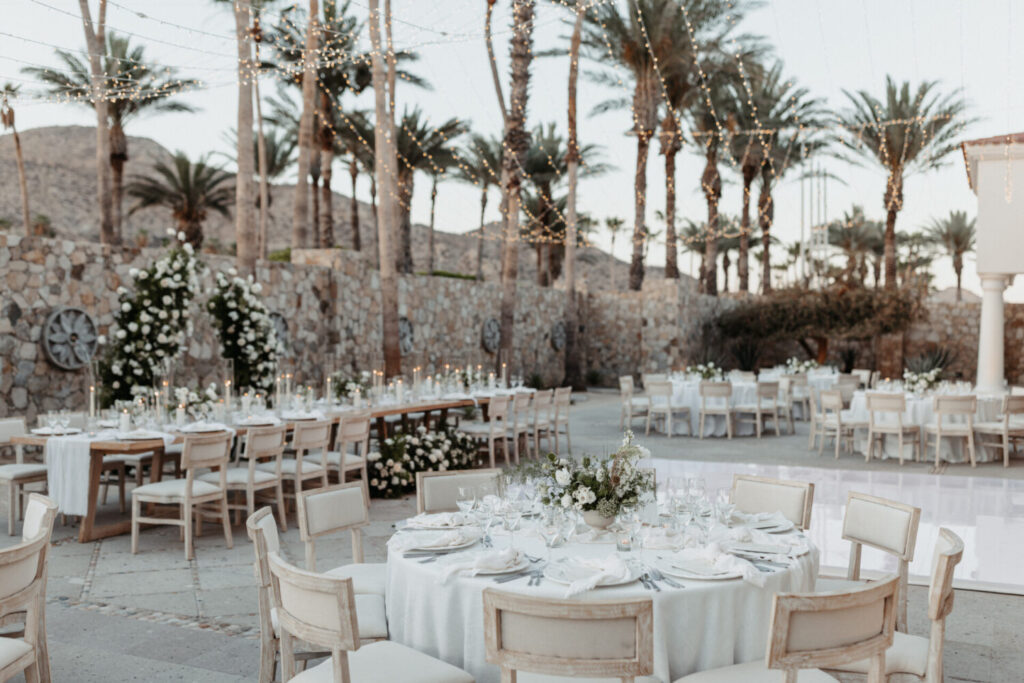 Beachside celebration at Hilton Los Cabos with floral tables, string lights, and a romantic ambiance under palm trees.