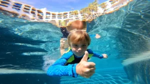 foto de un niño mostrando los pulgares hacia arriba desde un ángulo bajo dentro de las aguas