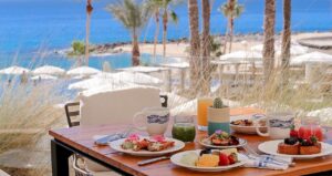 picture of a restaurant table full of food items with sea view