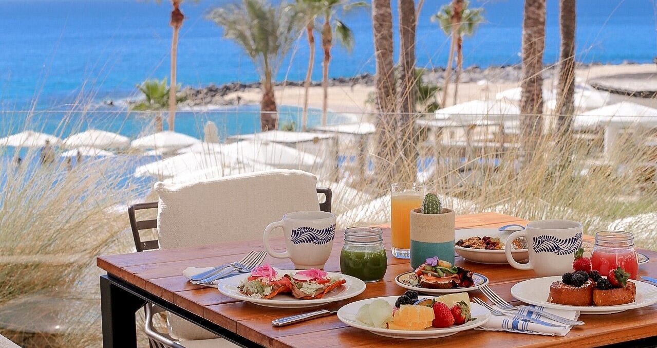 picture of a restaurant table full of food items with sea view