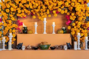 Traditional Day of the Dead altar with marigold flowers, candles, food, skulls, vibrant decorations.