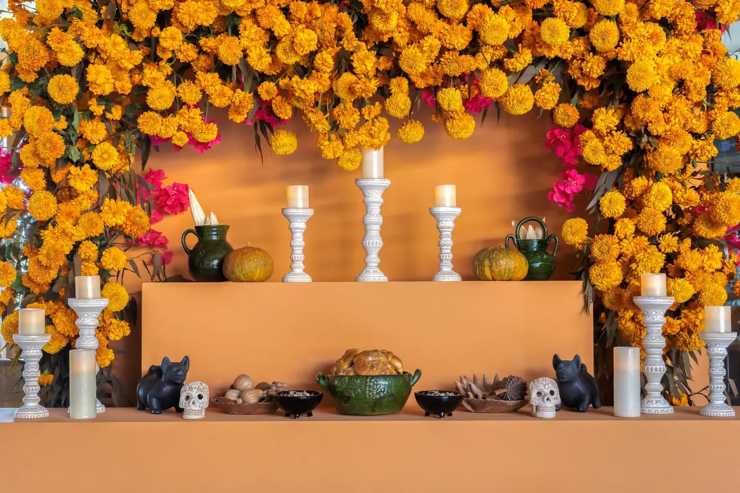 Altar tradicional del Día de Muertos con flores de cempasúchil, velas, comida, calaveras y decoraciones vibrantes.