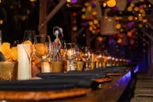 Mesa de cena adornada con flores de caléndula para la celebración del Día de los Muertos del Hilton Los Cabos, con velas, copas de vino y una figura tradicional de Catrina.
