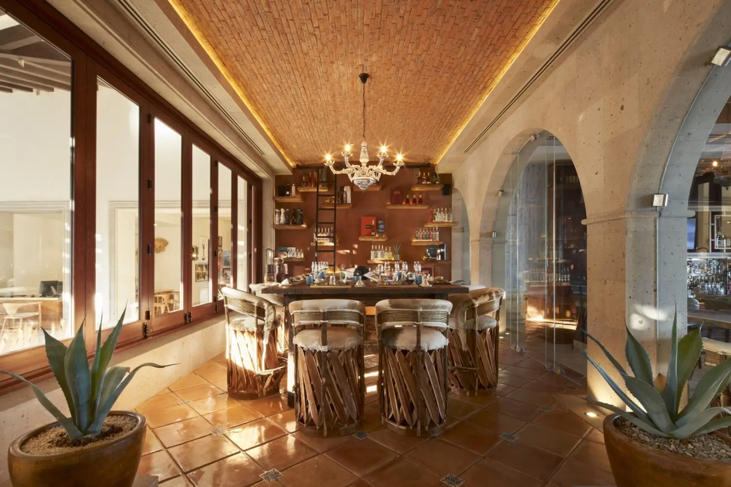 Elegant restaurant interior with arched doorways, chandelier, wooden tables, and warm lighting creating a refined dining atmosphere.