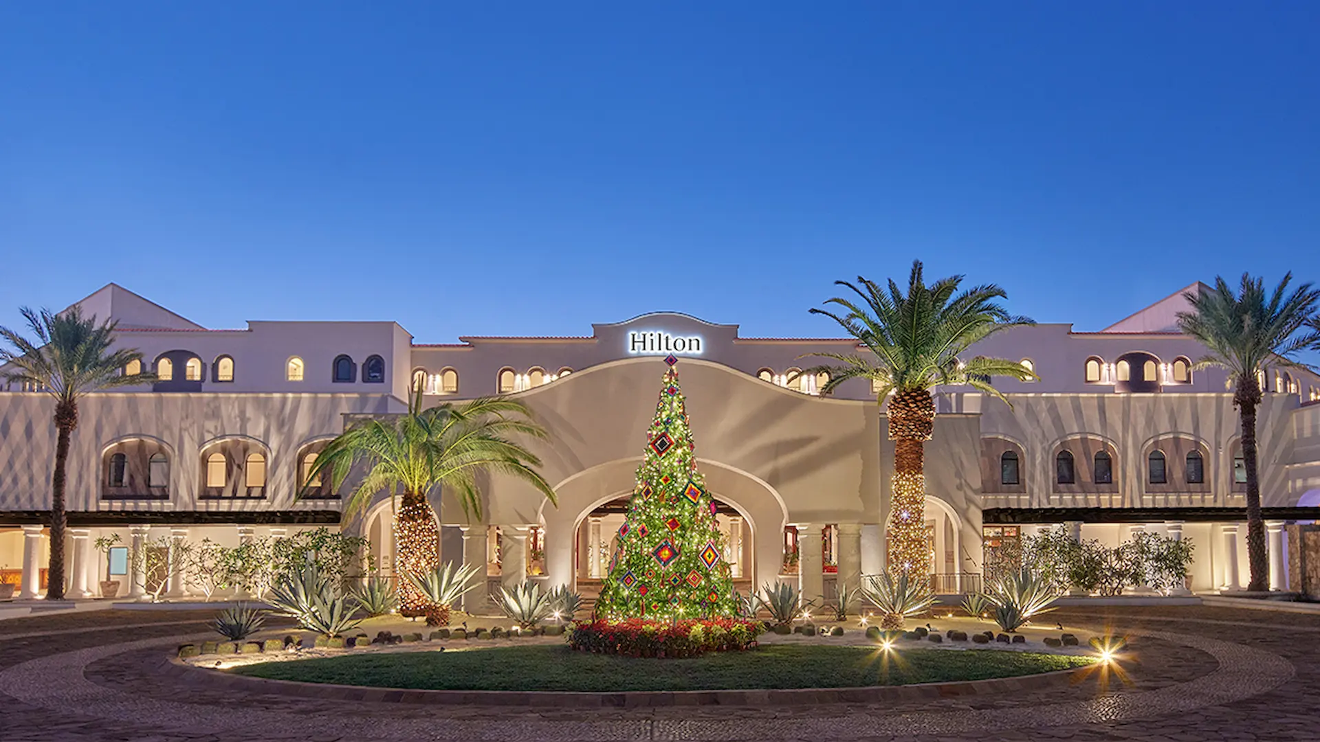 Group of friends sitting together outdoors, roasting marshmallows over a fire pit and chatting in a relaxed evening setting.