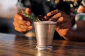 Cóctel artesanal en Hilton Los Cabos, adornado con romero y cítricos secos, resaltando la mixología artesanal del resort.