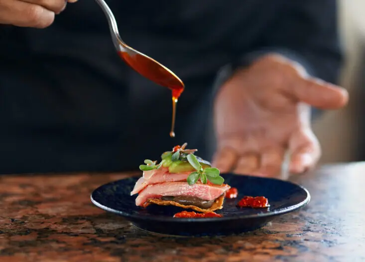 Gourmet plating at Hilton Los Cabos with delicate slices, vibrant sauce, and chef’s artistry in a refined culinary moment.