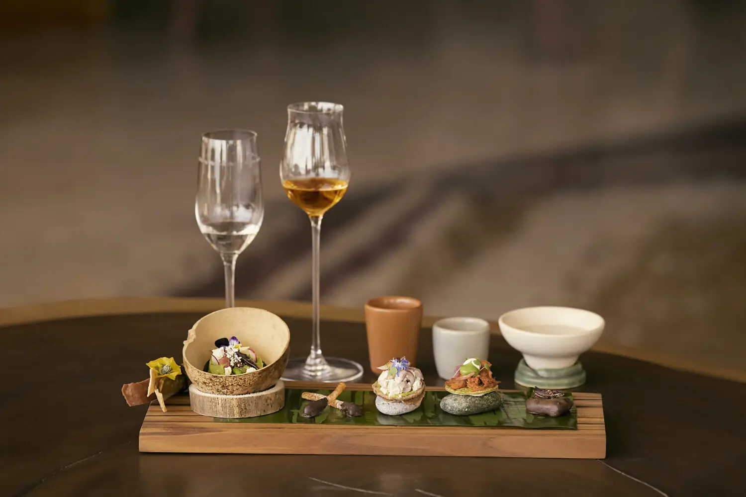 An image of 2 glasses filled with wine. A table of exquisite canapes and glasses of mezcal.