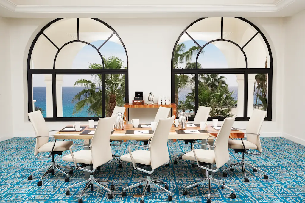 Ocean-view conference room with modern seating and large arched windows.