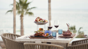 Cena elegante con vista al mar en Hilton Los Cabos con platillos gourmet, vino y ambiente tropical bajo palmeras ondulantes.