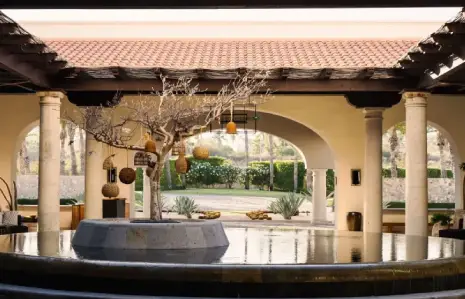 Courtyard at Hilton Los Cabos with holiday decor, a central fountain, and elegant arches surrounded by lush greenery.