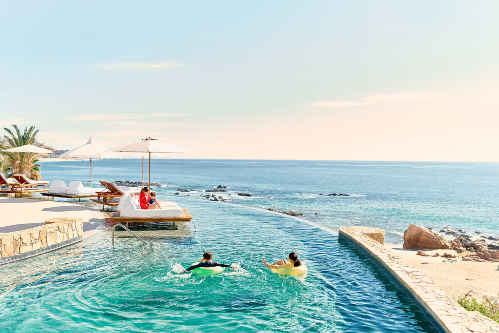 Summer 3 Infinity pool at hilton los cabos with ocean views, lounge chairs, and guests relaxing under the sun in serene luxury.
