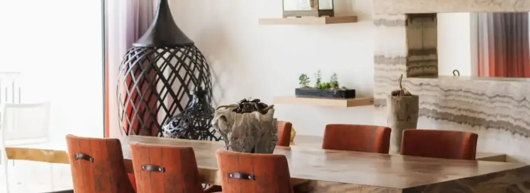 Modern dining area with a stone table, leather chairs, sculptural decor, and minimalist shelves in a luxury suite.